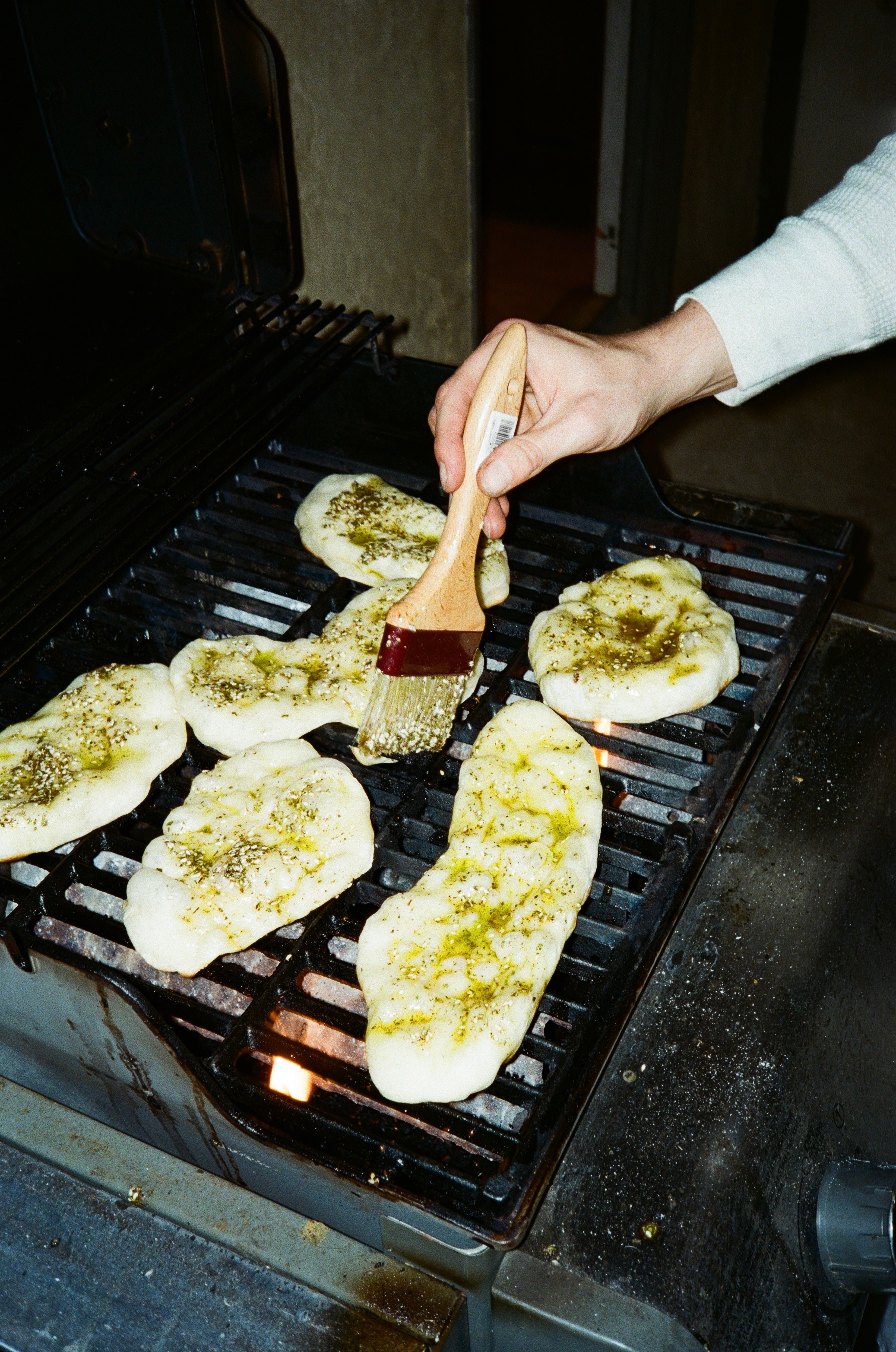 Za'atar flatbreads being brushed with oil over the grill